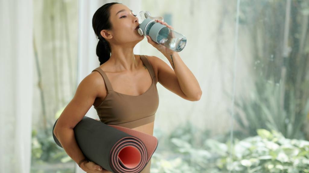 Member after class with water bottle and rolled mat in a sunlit studio, fictional Studio Form